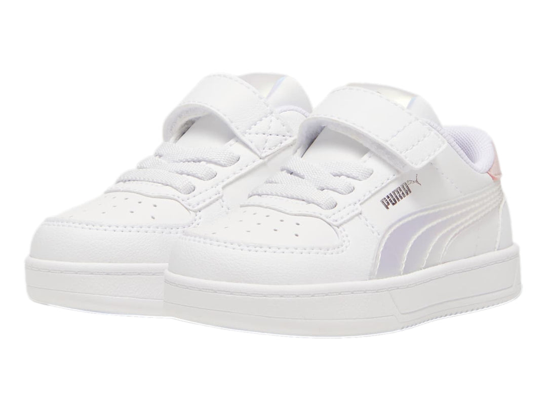 Tenis PUMA blancos para niños con detalles en rosa y plateado holográfico, cierre de agujetas y correa de velcro.