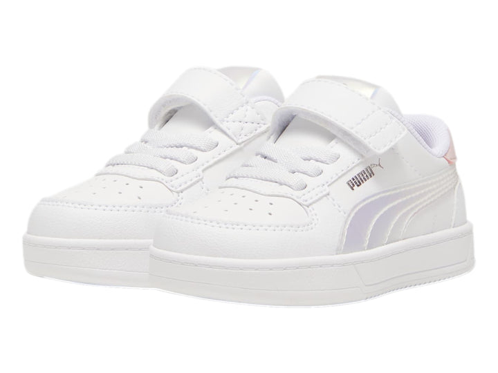 Tenis PUMA blancos para niños con detalles en rosa y plateado holográfico, cierre de agujetas y correa de velcro.