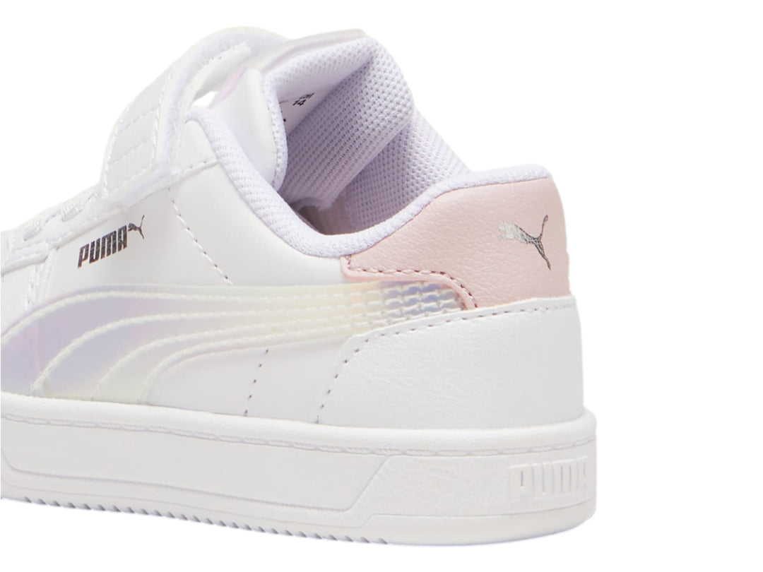 Tenis PUMA blancos para niños con detalles en rosa y plateado holográfico, cierre de agujetas y correa de velcro.