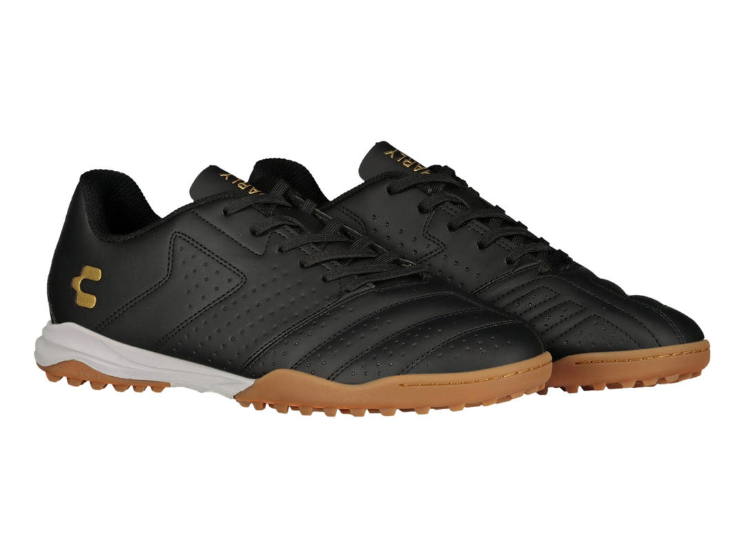 Zapato de fútbol Charly en color negro con suela blanca y marrón y logotipo dorado.