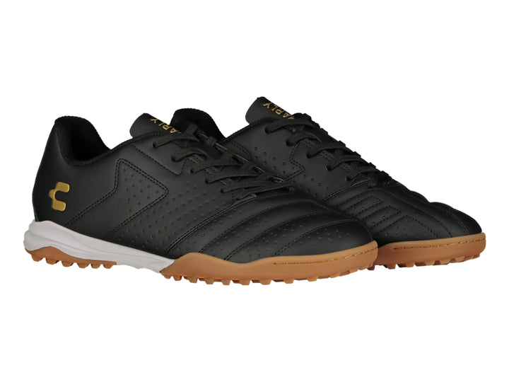 Zapato de fútbol Charly en color negro con suela blanca y marrón y logotipo dorado.
