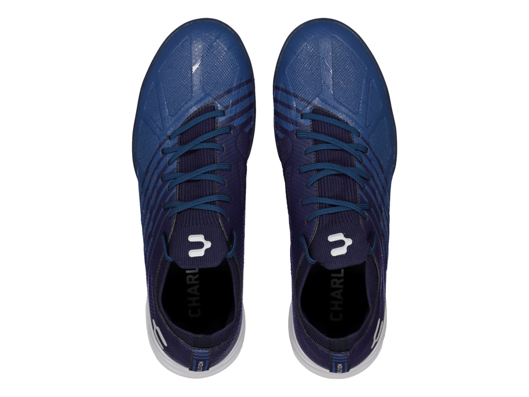 Calzado de fútbol Charly color azul marino con suela blanca y azul, diseño sintético para canchas artificiales.