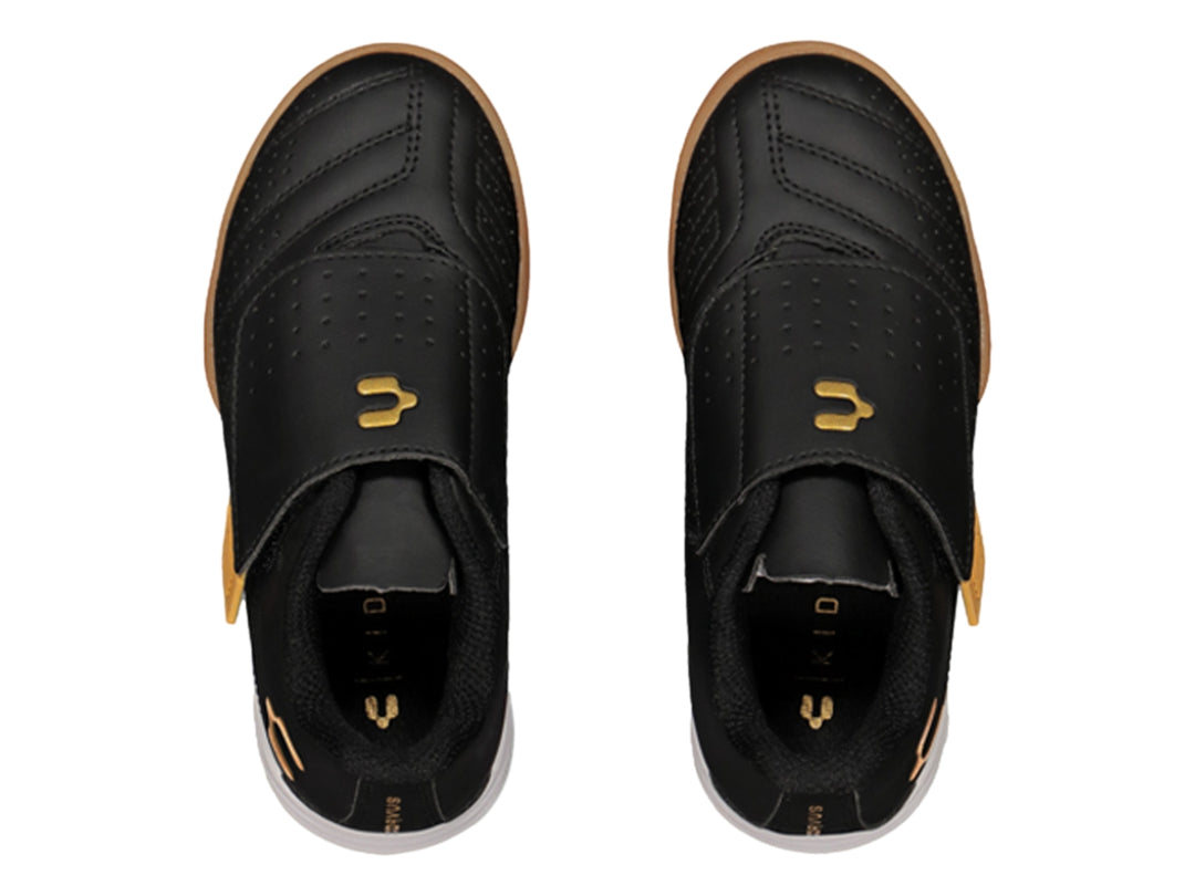 Zapato de fútbol Charly negro con detalles dorados y cierre de velcro.