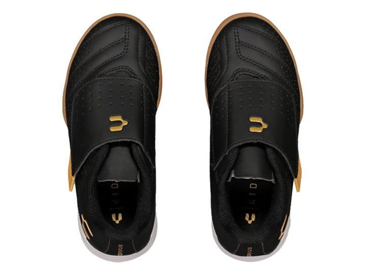 Zapato de fútbol Charly negro con detalles dorados y cierre de velcro.