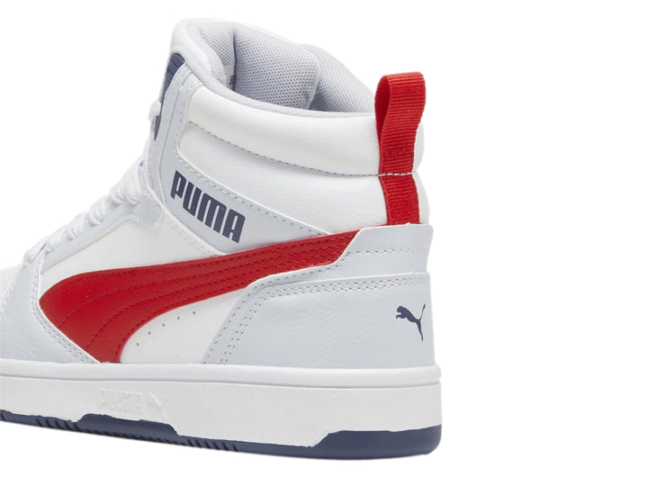 Tenis PUMA Rebound V6 Mid JR color blanco y plata con franja roja y detalles en azul marino.