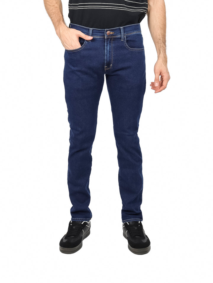 Hombre vistiendo un pantalón de mezclilla azul oscuro de corte ajustado y estilo casual.
