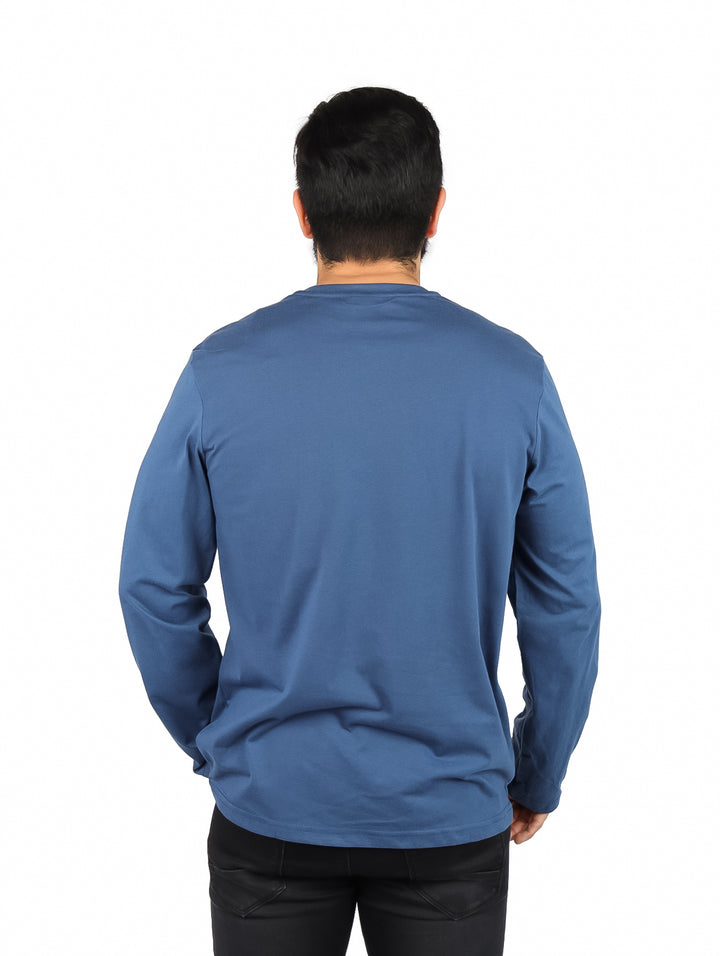 Hombre usando una playera de manga larga color petroleo con logotipo OGGI Jeans en el pecho.