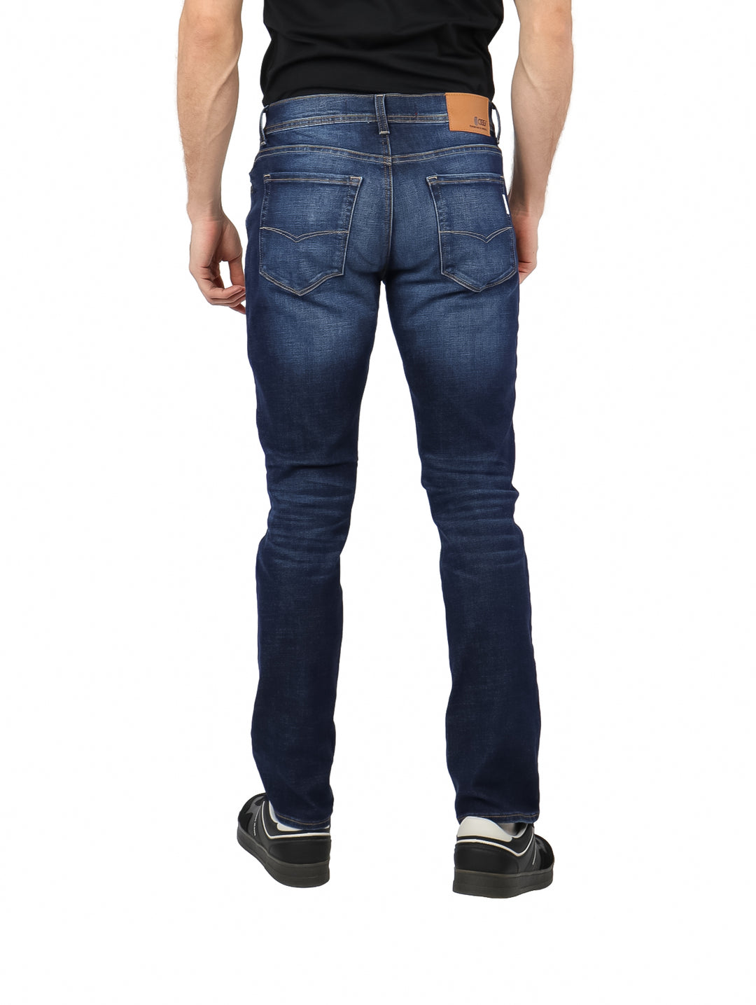 Hombre vistiendo pantalones de mezclilla azul oscuro con efecto lavado stone wash.