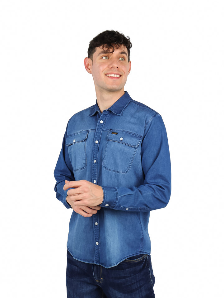 Hombre vistiendo una camisa de mezclilla azul de manga larga con corte slim fit.