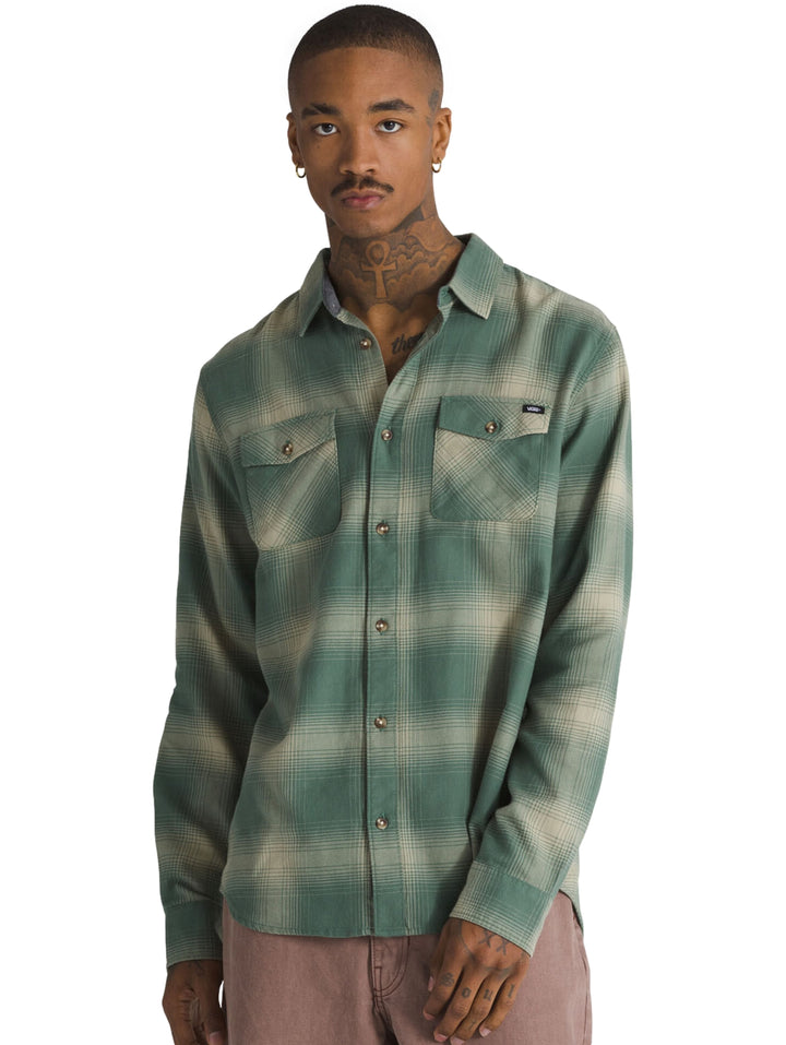 Hombre vistiendo camisa VANS de manga larga con estampado de cuadros en colores verde bosque y beige.