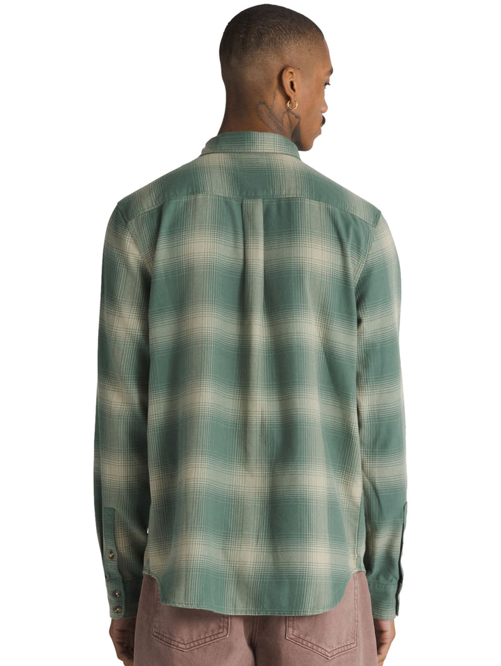 Hombre vistiendo camisa VANS de manga larga con estampado de cuadros en colores verde bosque y beige.