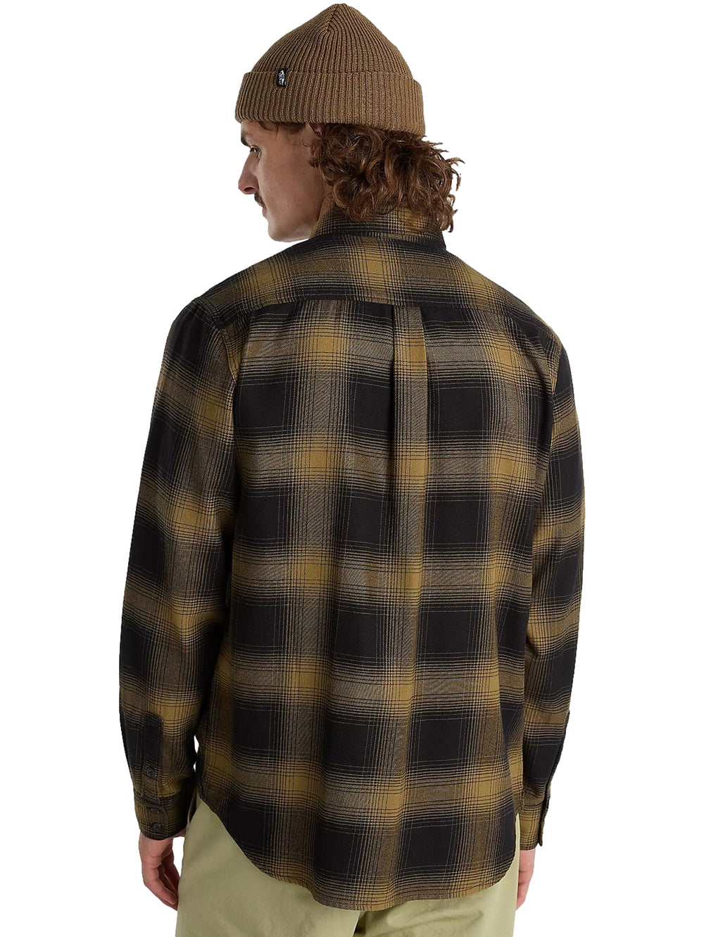 Hombre vistiendo camisa de franela a cuadros en colores negro y verde olivo, gorro marrón y pantalones beige.