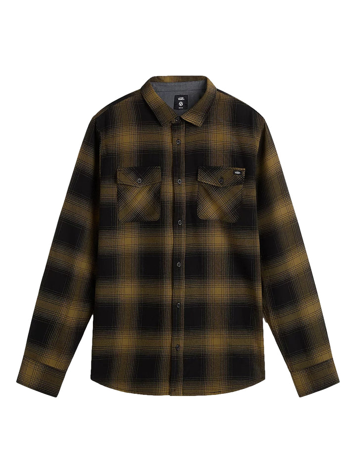 Hombre vistiendo camisa de franela a cuadros en colores negro y verde olivo, gorro marrón y pantalones beige.