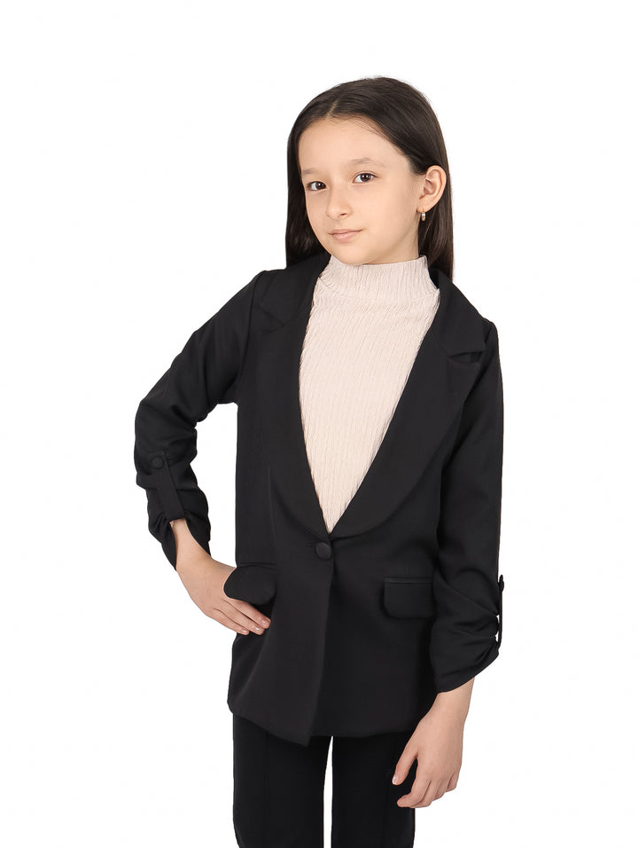 Niña vistiendo un saco negro elegante sobre un suéter beige.