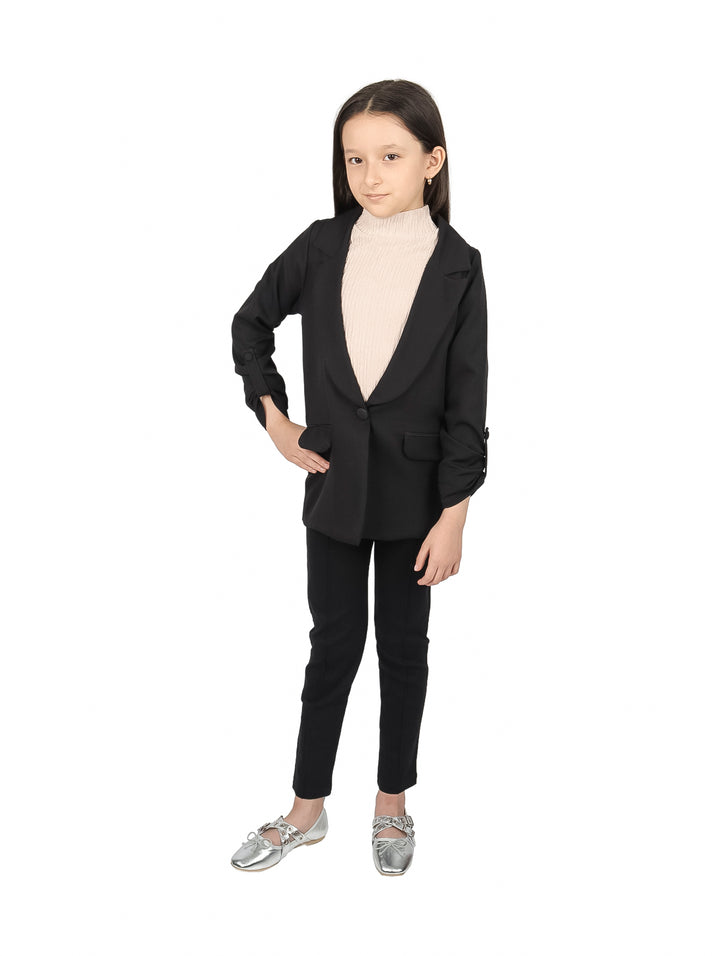 Niña vistiendo un saco negro elegante sobre un suéter beige.