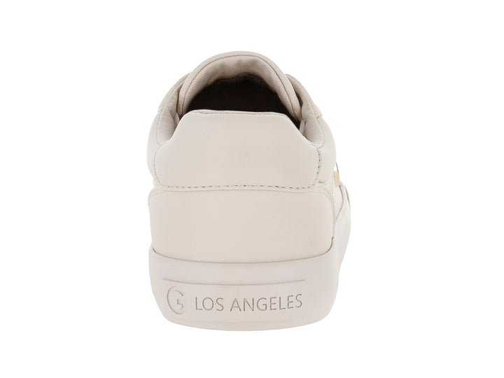 Tenis casuales color ivory con cordones blancos y detalle metálico lateral en forma de G.