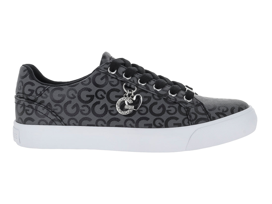 Tenis casuales negros con estampado de letras G, suela blanca y un dije metálico en las agujetas.