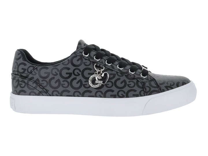 Tenis casuales negros con estampado de letras G, suela blanca y un dije metálico en las agujetas.