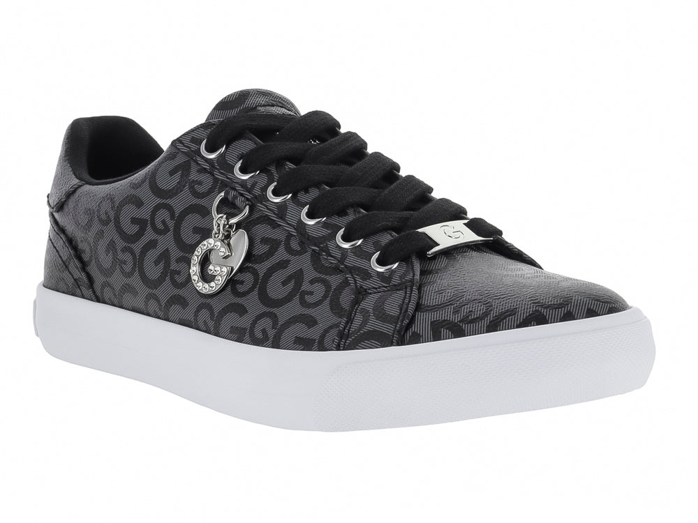 Tenis casuales negros con estampado de letras G, suela blanca y un dije metálico en las agujetas.