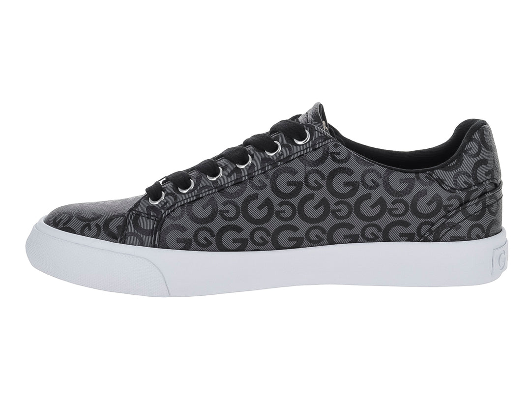 Tenis casuales negros con estampado de letras G, suela blanca y un dije metálico en las agujetas.