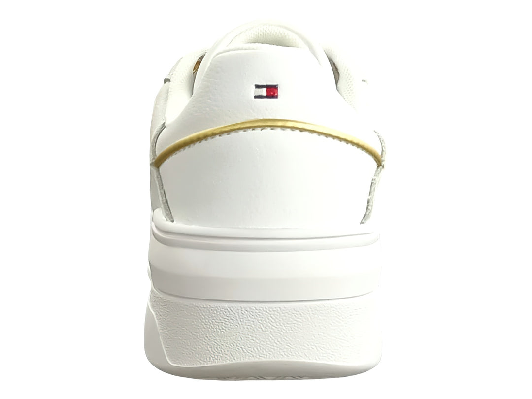 Tenis blancos Tommy Hilfiger estilo basket con detalles dorados y suela blanca ancha para mujer.