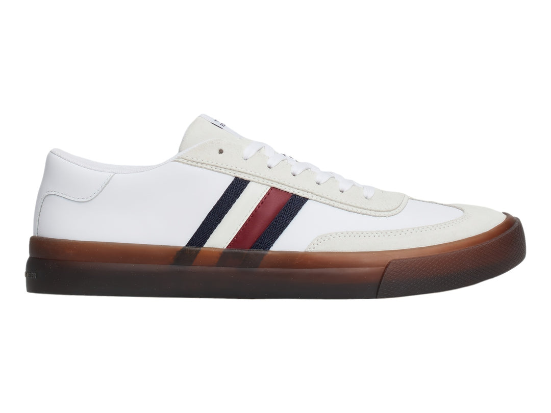 Tenis blancos de corte bajo con rayas laterales en azul y rojo y suela color café.