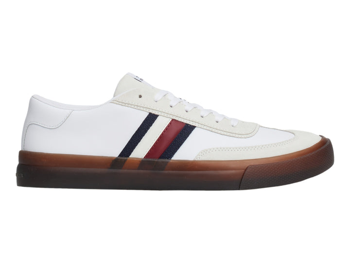 Tenis blancos de corte bajo con rayas laterales en azul y rojo y suela color café.