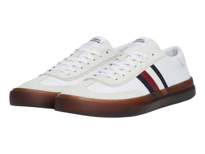 Tenis blancos de corte bajo con rayas laterales en azul y rojo y suela color café.