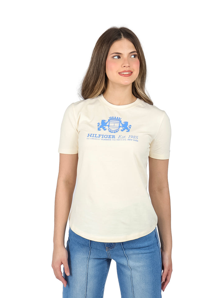 Mujer vistiendo una camiseta de manga corta color calico con logotipo azul en el pecho.