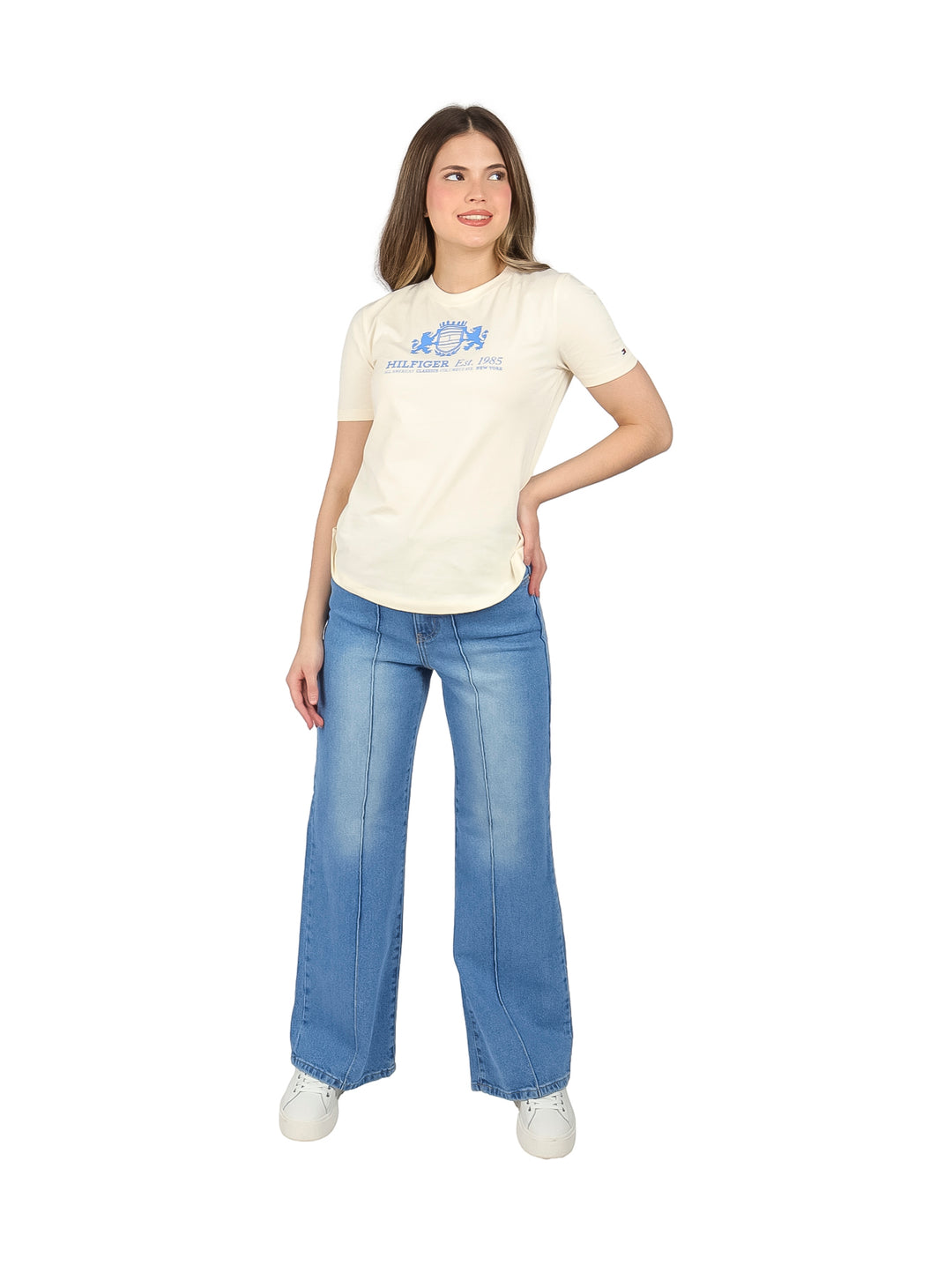 Mujer vistiendo una camiseta de manga corta color calico con logotipo azul en el pecho.
