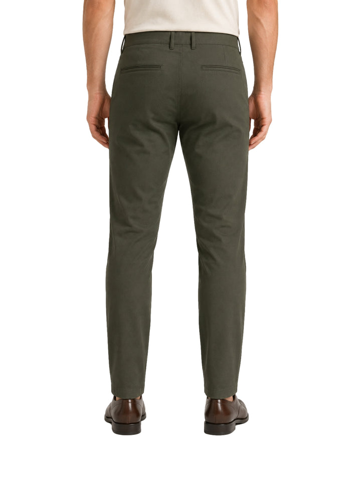 Hombre vistiendo un pantalón color verde oliva de corte slim fit y zapatos cafés.