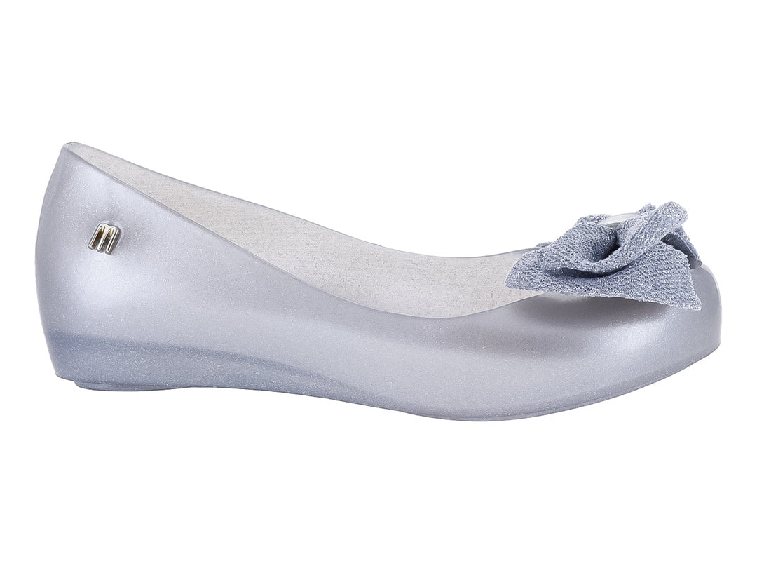 Zapato infantil Mini Melissa color plata con detalle de moño en la parte frontal.