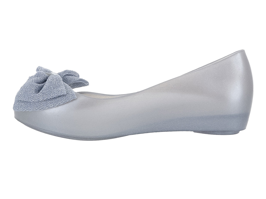 Zapato infantil Mini Melissa color plata con detalle de moño en la parte frontal.