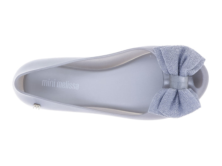 Zapato infantil Mini Melissa color plata con detalle de moño en la parte frontal.