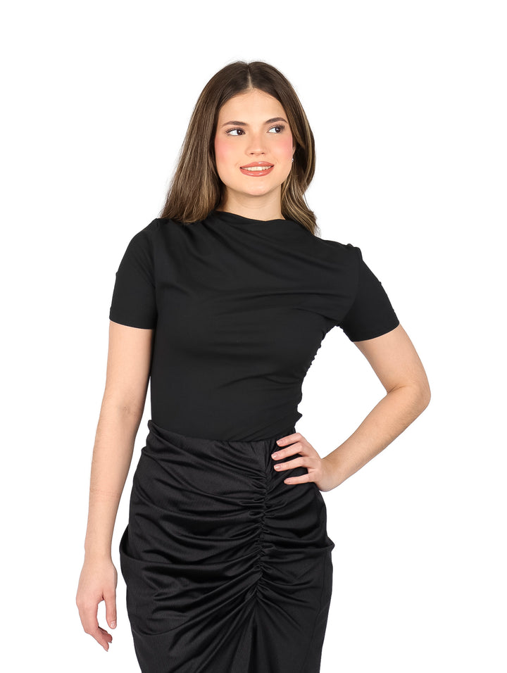Mujer vistiendo blusa negra ajustada de manga corta y falda negra con fruncido frontal.