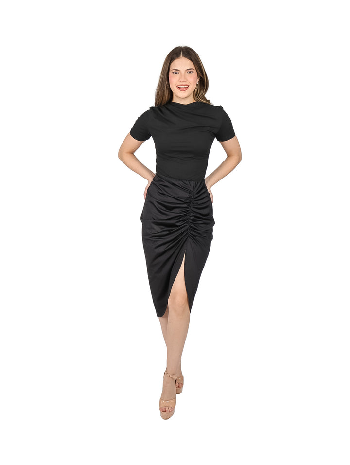 Mujer vistiendo blusa negra ajustada de manga corta y falda negra con fruncido frontal.