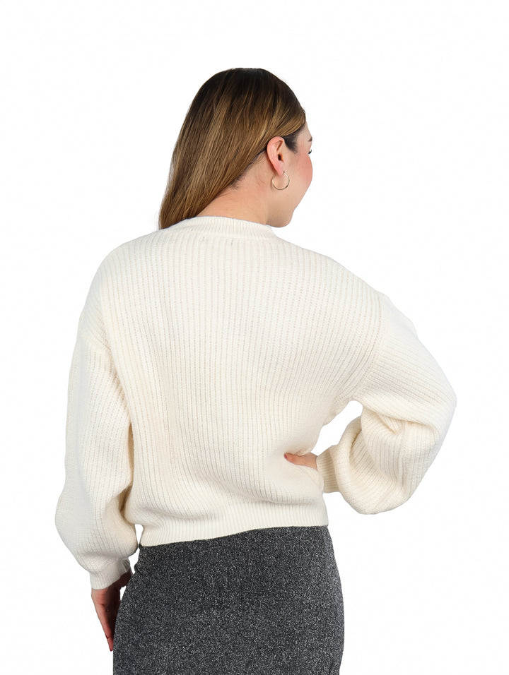 Mujer vistiendo un suéter tejido color beige de manga larga y cuello redondo.