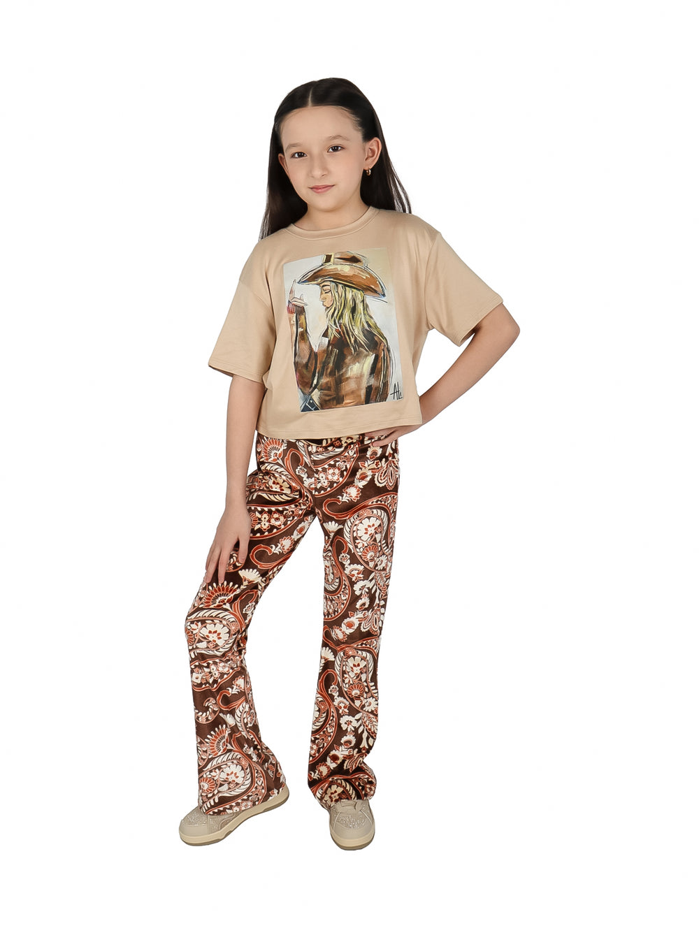 Vista trasera de conjunto para niña con camiseta beige y pantalones marrones estampados.