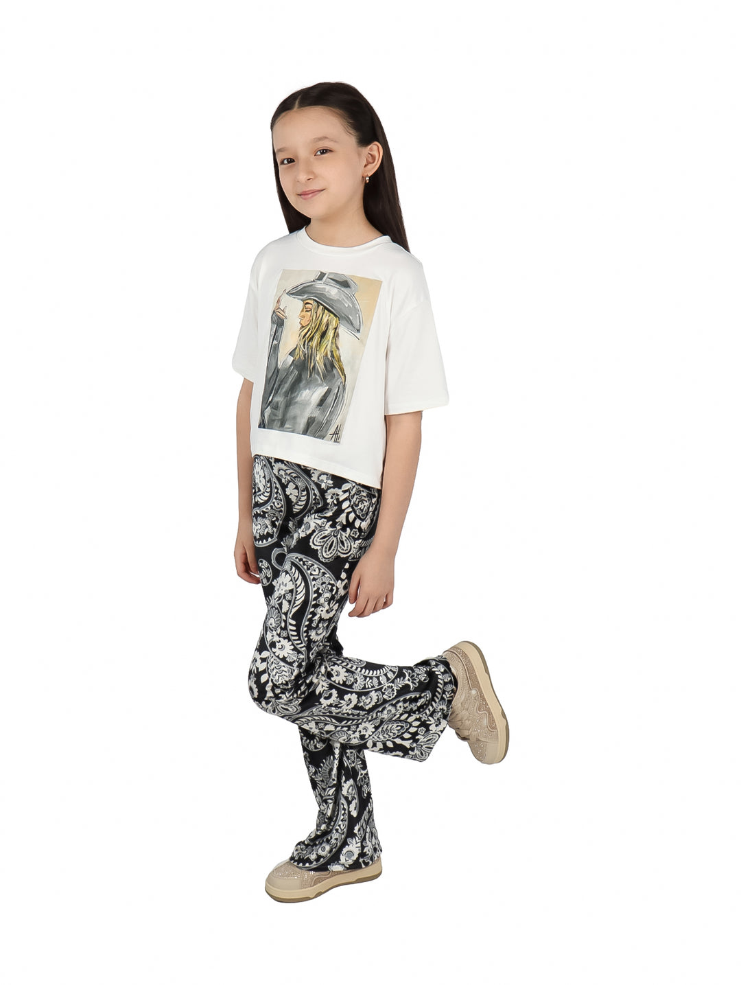 Conjunto para niña con camiseta blanca estampada y pantalón negro con patrones blancos.