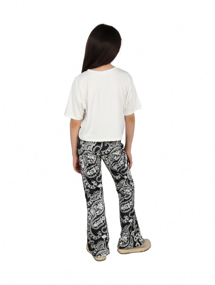 Conjunto para niña con camiseta blanca estampada y pantalón negro con patrones blancos.