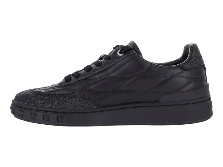 Tenis negros Guess con diseño acolchado y detalles brillantes en la punta y el talón.
