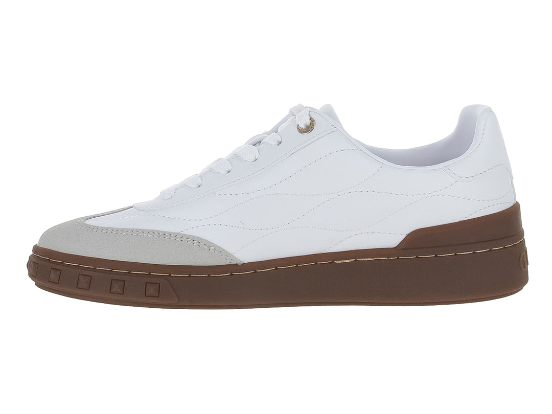 Tenis blancos Guess con textura acolchada, punta gris y suela gruesa color café.