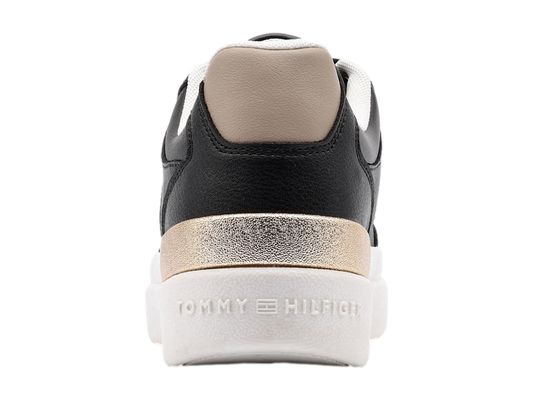 Tenis negros de Tommy Hilfiger con suela blanca y detalles dorados en el talón.