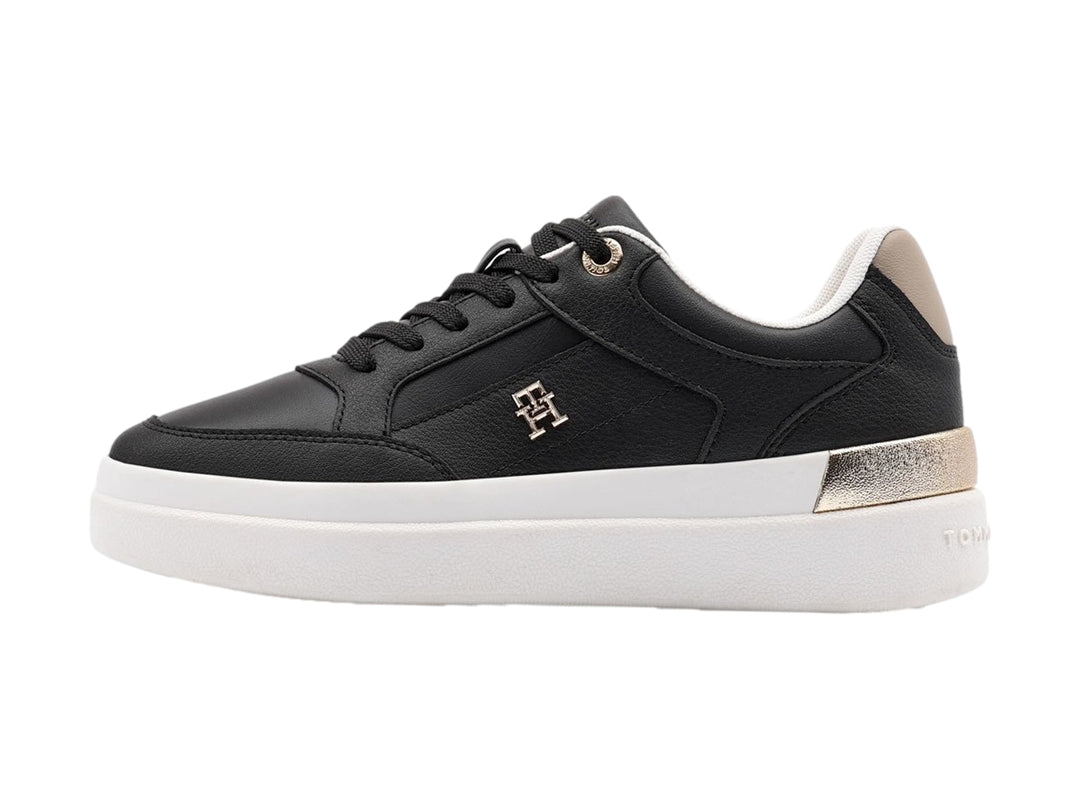 Tenis negros de Tommy Hilfiger con suela blanca y detalles dorados en el talón.
