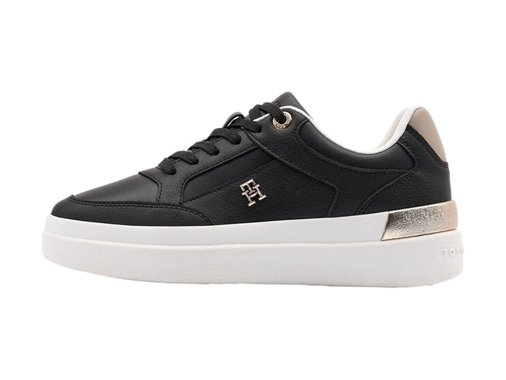 Tenis negros de Tommy Hilfiger con suela blanca y detalles dorados en el talón.