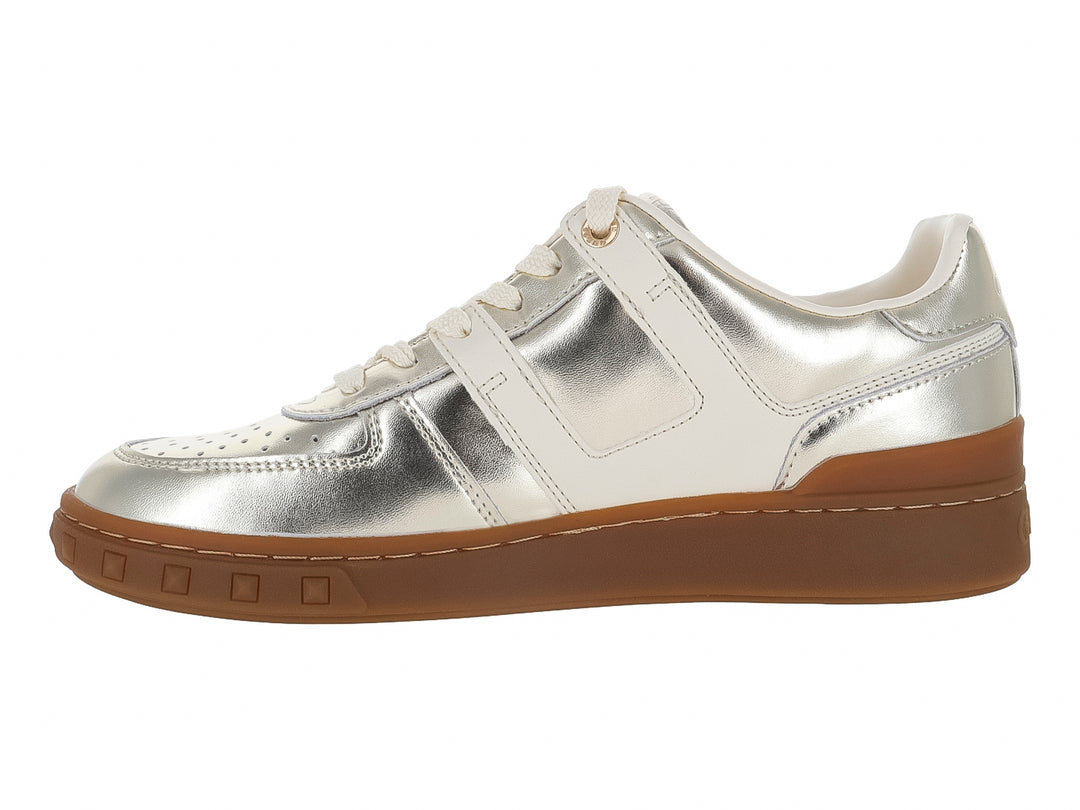 Tenis GUESS color dorado metálico con detalles en blanco y suela gruesa color café.