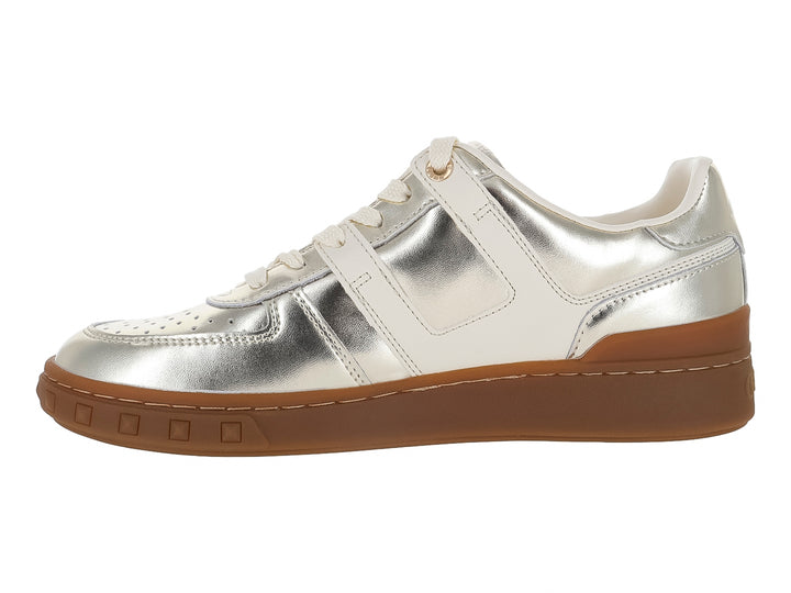 Tenis GUESS color dorado metálico con detalles en blanco y suela gruesa color café.