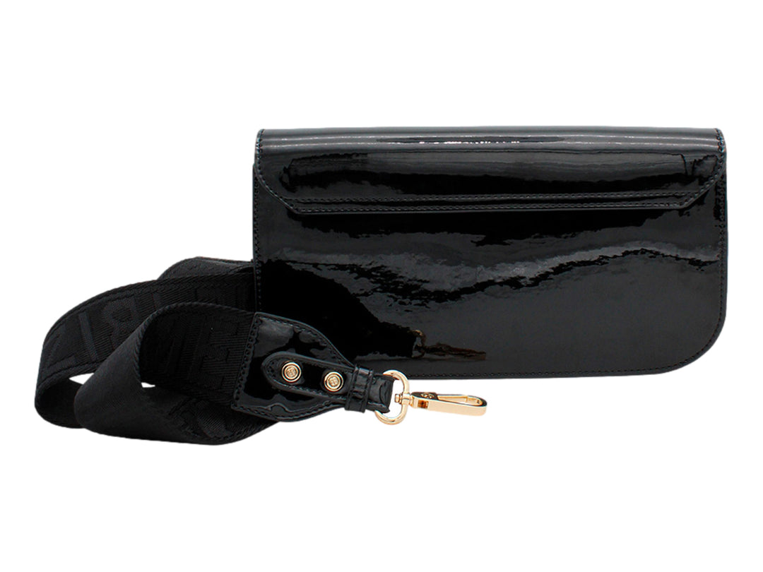 Bolso de mano negro en acabado charol brillante con cierre circular dorado y correa larga.