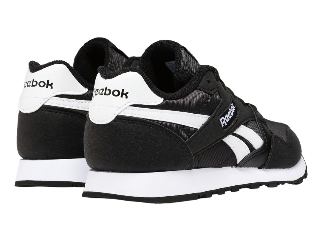 Tenis deportivos Reebok color negro con franjas y suela blanca.