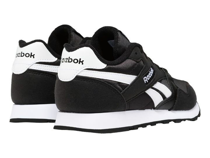 Tenis deportivos Reebok color negro con franjas y suela blanca.